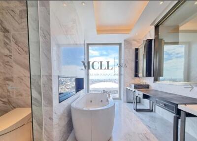 Luxurious bathroom with marble walls, standalone bathtub, large window with city view, and contemporary design