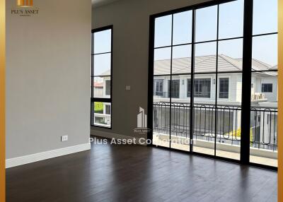 Spacious living area with large windows and hardwood flooring