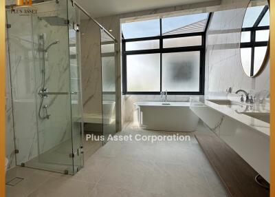 Modern bathroom with glass shower, freestanding bathtub, and large windows