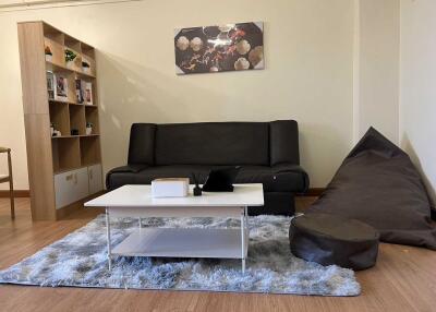 Modern living room with black sofa, a bean bag, coffee table, and wall art