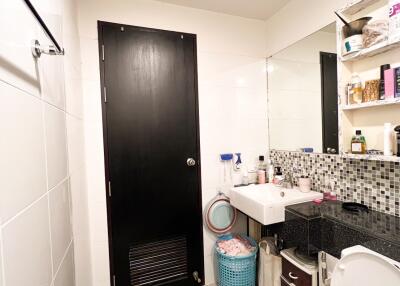 Compact bathroom with black door and countertop, white sink, and large wall mirror