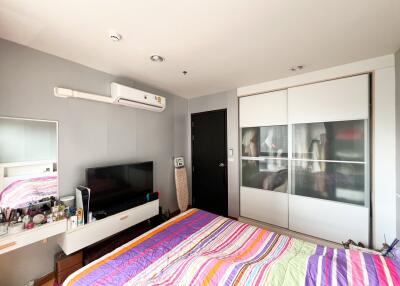 Modern bedroom with striped bedspread, built-in wardrobes, and wall-mounted television