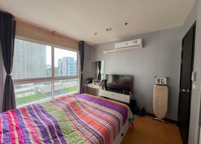 Bedroom with colorful bedspread, TV, window, and various furnishings