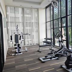 Well-equipped gym with exercise machines, weights, and large windows with natural light