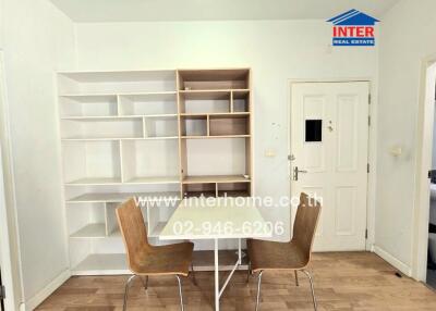 Minimalist dining area with wooden floor and white shelves