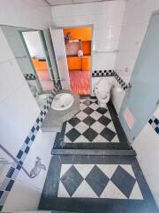 Bathroom with checkered tile flooring, toilet, sink, and view into an adjacent room