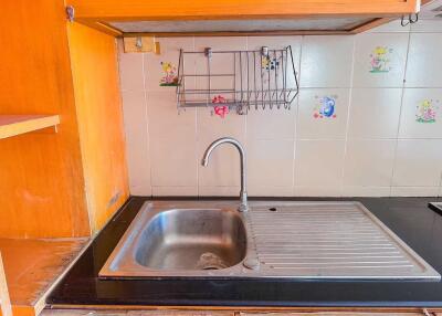 A kitchen sink with drying rack and tiled backsplash