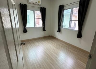 Empty bedroom with wooden floor, curtains, and air conditioning