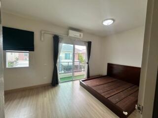 Bedroom with wooden bed frame, large window, and air conditioner