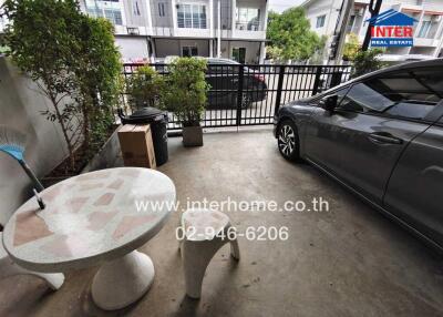 Covered outdoor parking space with a car, table, and some greenery