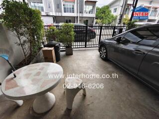 Covered outdoor parking space with a car, table, and some greenery