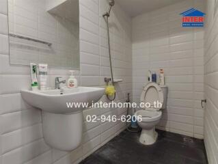 Modern bathroom with white tiles, sink, mirror, toilet and shower