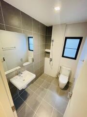 Modern bathroom with grey tiles, a large mirror, and modern fixtures