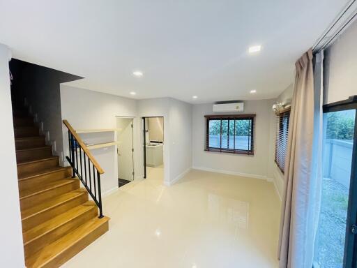 Spacious living room with wooden staircase and large windows