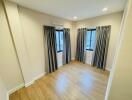 Empty bedroom with wooden flooring and curtains