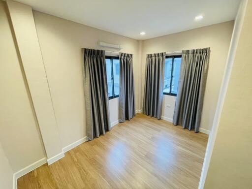 Empty bedroom with wooden flooring and curtains