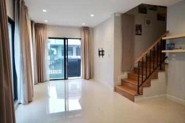 Spacious and well-lit living room with sliding glass doors and stairway access