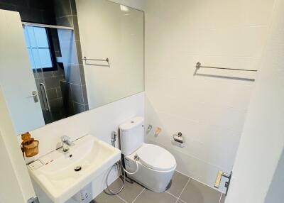 Modern bathroom with large mirror, sink, toilet, and tiled floor