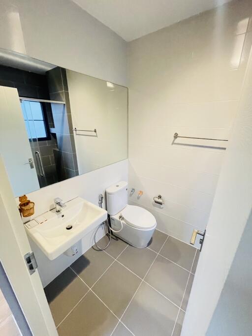 Modern bathroom with large mirror, sink, toilet, and tiled floor