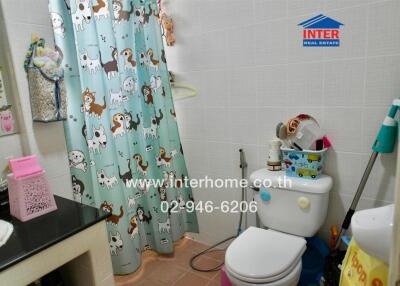 Bathroom with animal-themed shower curtain, white toilet, bathroom accessories, and cleaning tools