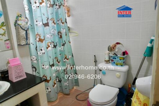 Bathroom with animal-themed shower curtain, white toilet, bathroom accessories, and cleaning tools