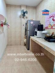 Small kitchen with tiled walls and floor, featuring a refrigerator, microwave, and other appliances