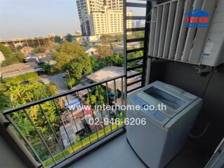 Apartment balcony with washing machine and view of surrounding buildings