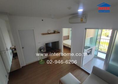 Modern living area with TV, small fan, and access to bedroom and balcony