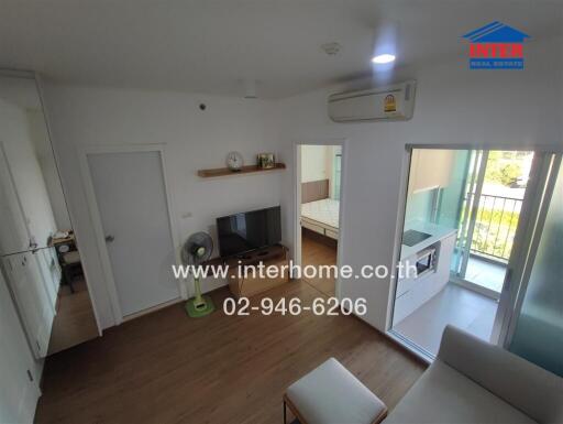 Modern living area with TV, small fan, and access to bedroom and balcony