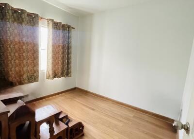 Empty bedroom with wooden flooring and small furniture