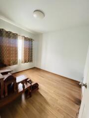 Empty bedroom with wooden flooring and small furniture