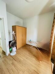 Simple bedroom with wooden floor, wardrobe, and ironing board