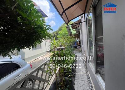 View of garden path beside house with white fence and canopy