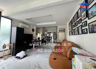 Living room with brown sofa, photo wall, and open view to the dining area
