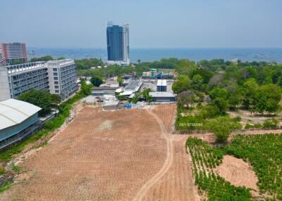 Aerial view of land plot near coastal area with neighboring buildings and water in the background