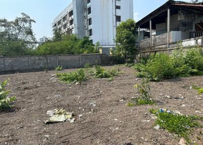 Vacant lot with sparse vegetation and surrounding buildings