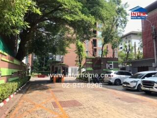 Building entrance with parking area and surrounding greenery