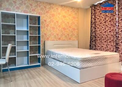 Modern bedroom with bed, bookshelf, chair, and patterned curtains