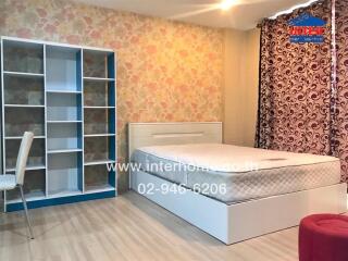 Modern bedroom with bed, bookshelf, chair, and patterned curtains