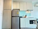 Modern compact kitchen with fridge, cabinets, and countertop appliances