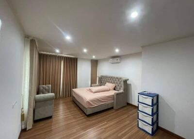 Spacious bedroom with wooden flooring, large bed, air conditioner, and a single chair