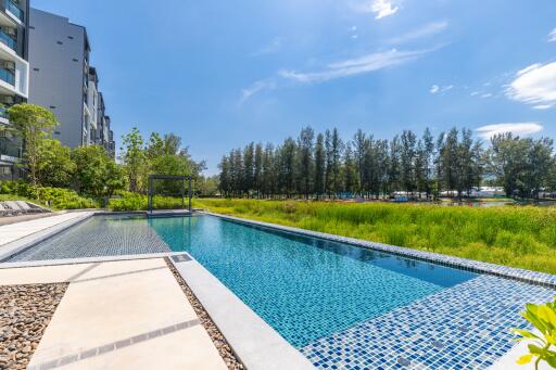 Outdoor swimming pool area with surrounding greenery and clear sky