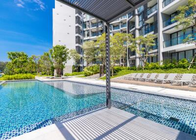 Outdoor swimming pool area with modern apartment building in the background