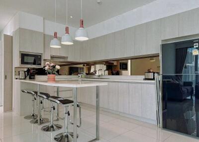 Modern kitchen with white cabinetry, high chairs, and hanging lights