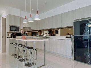 Modern kitchen with white cabinetry, high chairs, and hanging lights