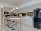 Modern kitchen with white cabinetry, high chairs, and hanging lights