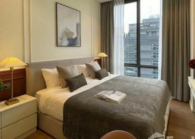 Cozy bedroom with a large bed, nightstands, lamps, and a large window with city view
