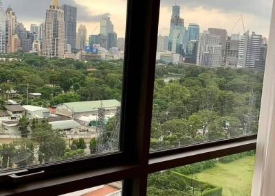 View of city skyline and green park from window