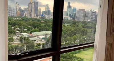 View of city skyline and green park from window