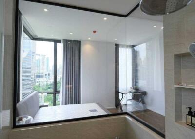 Modern bathroom with glass partition overlooking a bedroom with city view